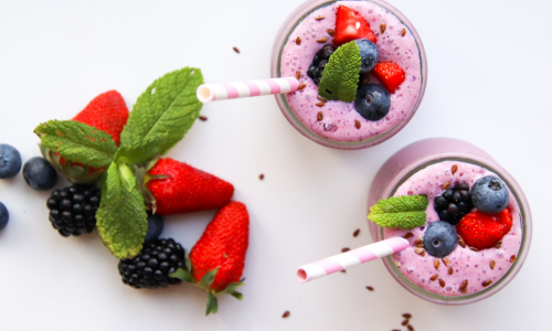 Two glasses of smoothies with strawberry and blackberry are lying on the table.