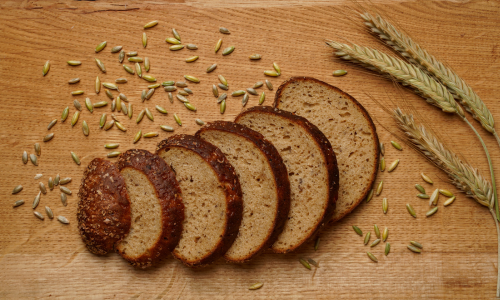 Slices of Brown Bread are placed on table with some grains.